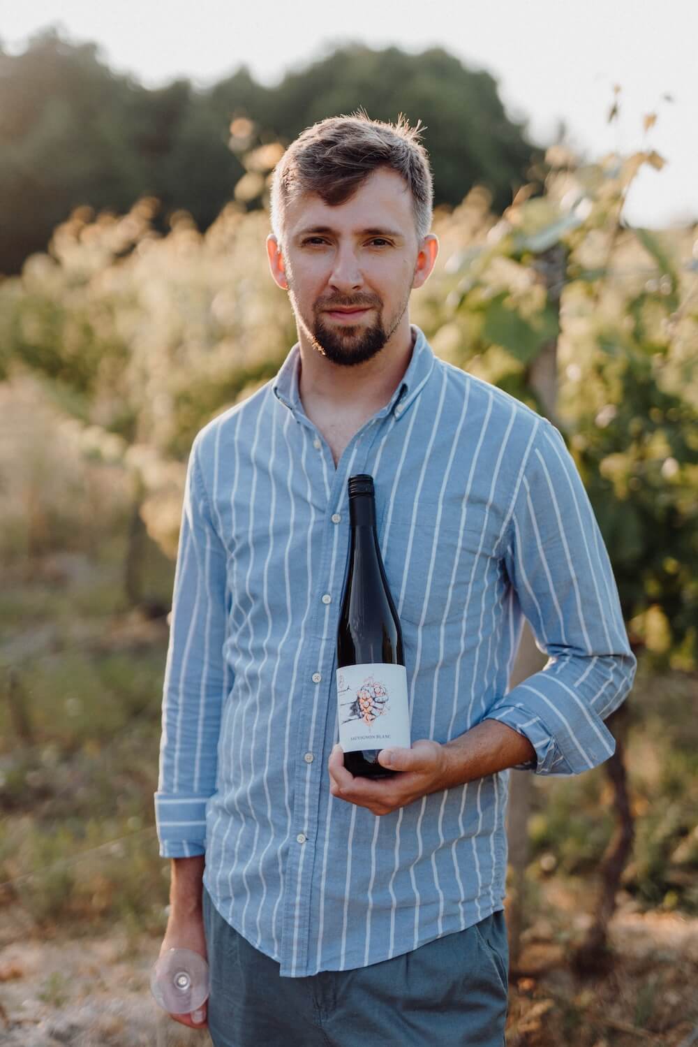 Vinár s fľašou vína vo vinici